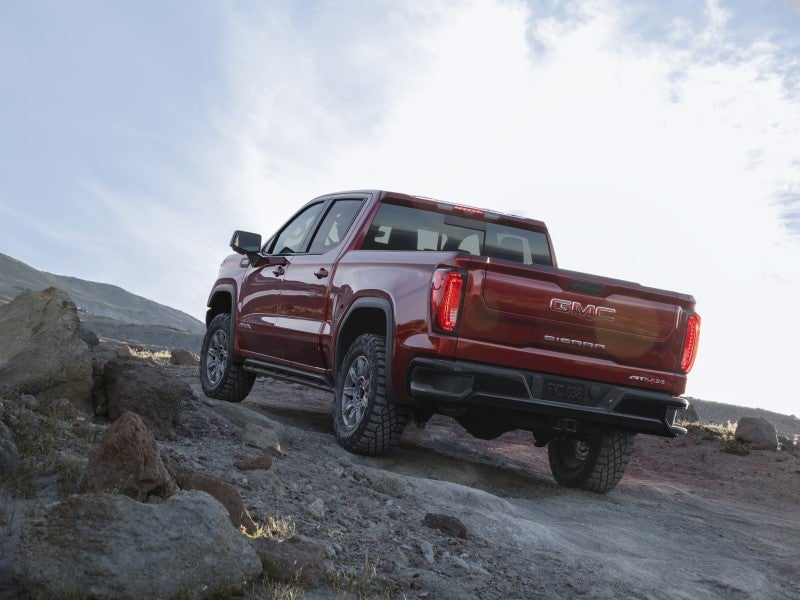 A red 2026 GMC Sierra 1500 drives up a dirt rocky road.